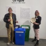 Two people standing by recycle bins